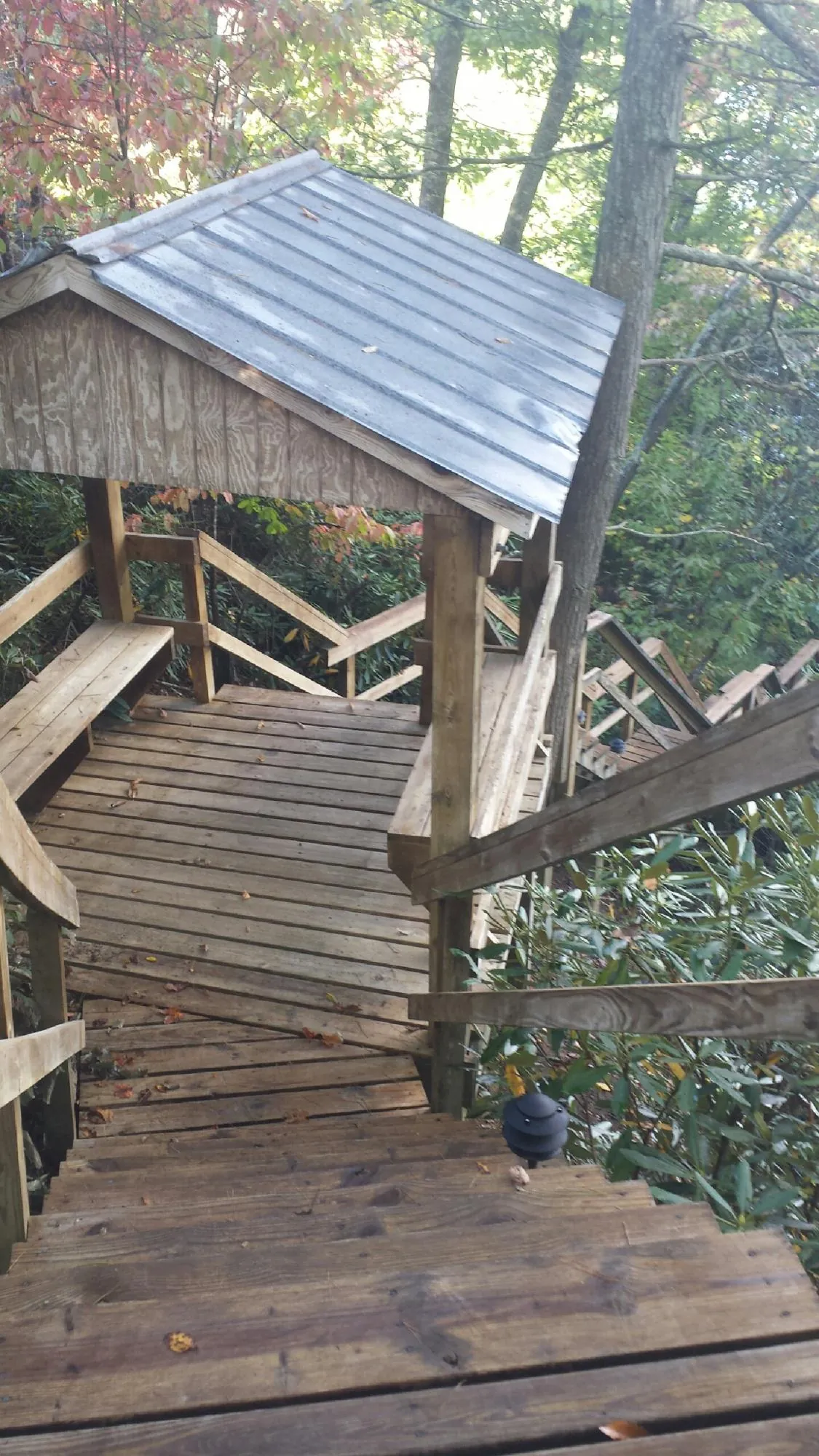 Metal roofed shelter over wooden steps on a wooded walkway — Skylight Repair & Installation work by our crew in Hartland